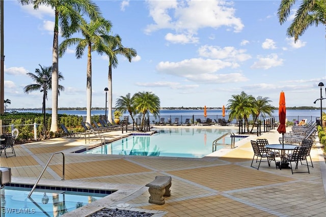 pool with a water view, a patio area, and fence