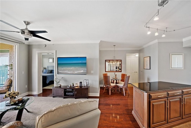 living area with ceiling fan with notable chandelier, ornamental molding, dark wood finished floors, and baseboards