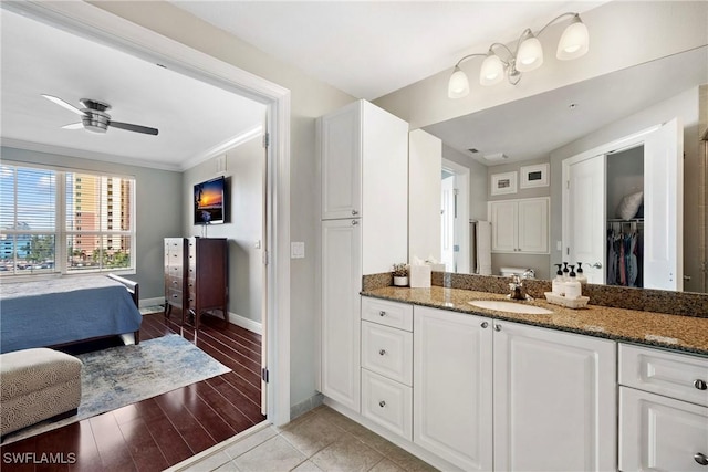 bathroom featuring crown molding, a ceiling fan, vanity, wood finished floors, and baseboards