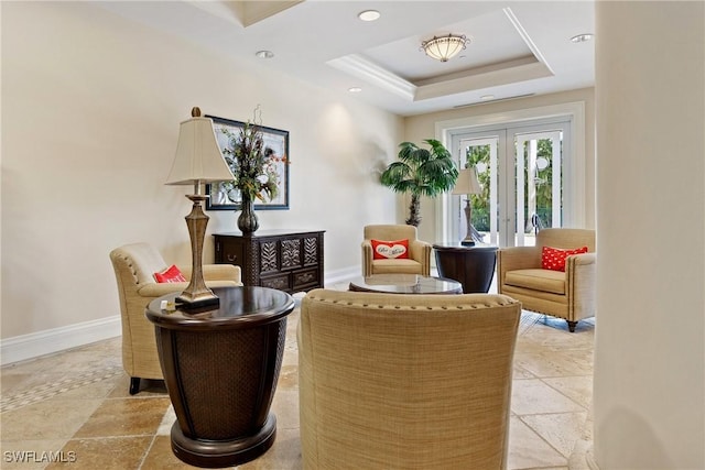 sitting room featuring stone tile floors, recessed lighting, baseboards, french doors, and a raised ceiling