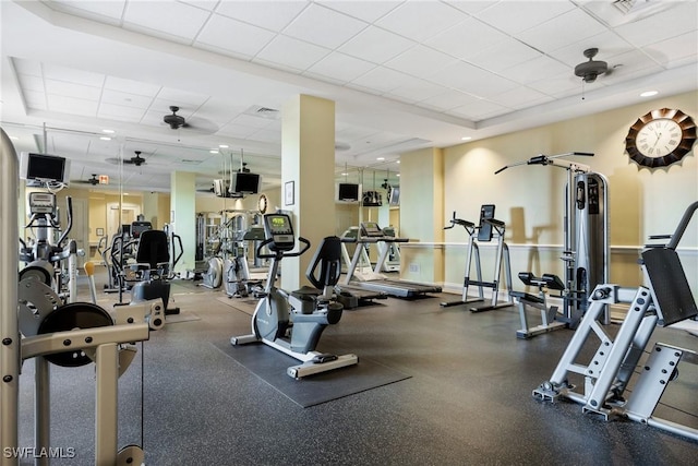 gym featuring a paneled ceiling, baseboards, and a ceiling fan