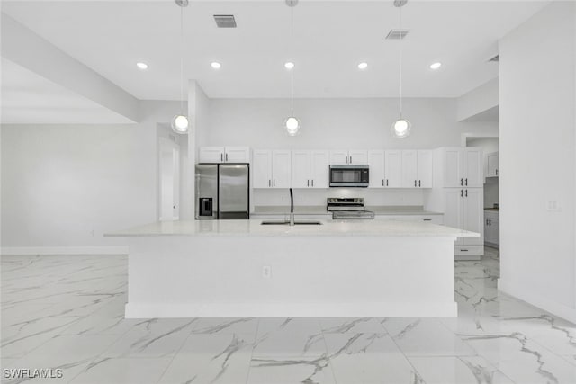 kitchen with light stone counters, a large island, hanging light fixtures, appliances with stainless steel finishes, and a sink