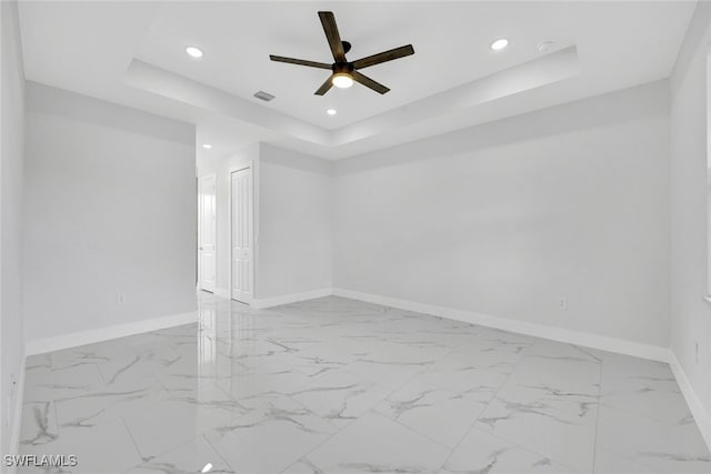 unfurnished room featuring a tray ceiling, recessed lighting, visible vents, a ceiling fan, and baseboards