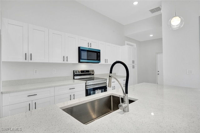 kitchen featuring light stone counters, visible vents, electric range, white cabinets, and a sink