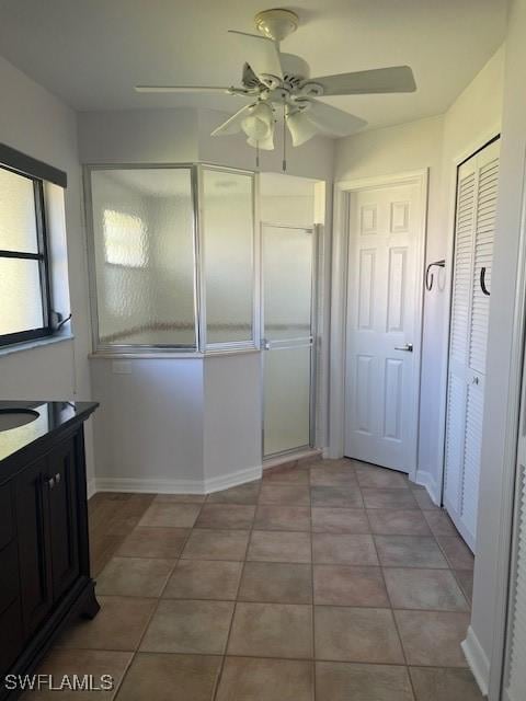 kitchen featuring ceiling fan, light tile patterned flooring, a sink, and baseboards