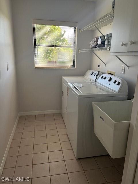 laundry room featuring light tile patterned flooring, washing machine and dryer, cabinet space, and baseboards