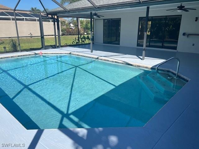 outdoor pool with glass enclosure, a ceiling fan, and a patio