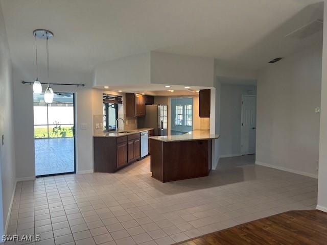 kitchen with light countertops, open floor plan, white dishwasher, a sink, and a peninsula