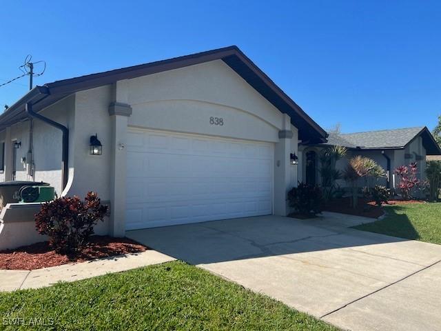 view of front facade with concrete driveway, an attached garage, and stucco siding