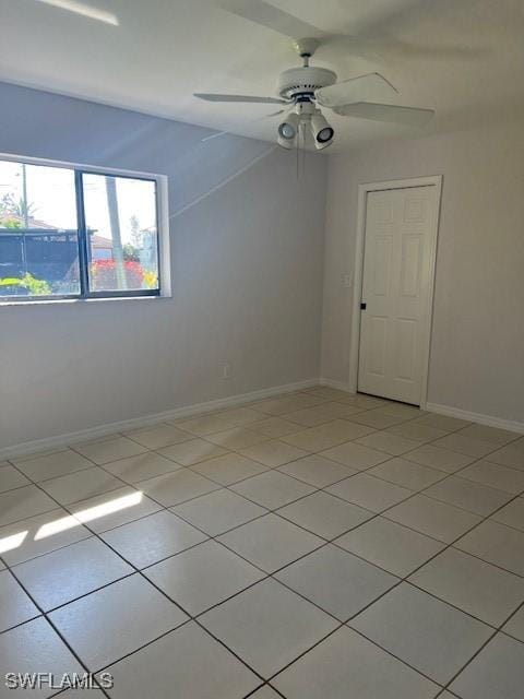 empty room with ceiling fan, baseboards, and light tile patterned floors