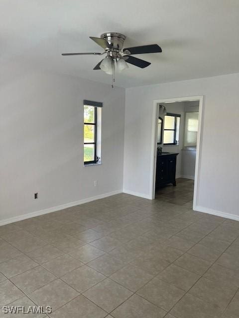 spare room with a ceiling fan and baseboards