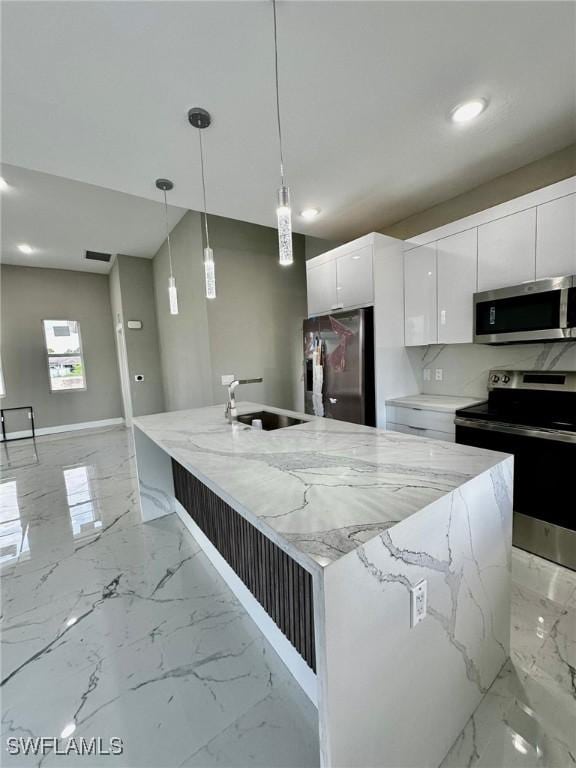 kitchen with a center island with sink, appliances with stainless steel finishes, white cabinets, and pendant lighting