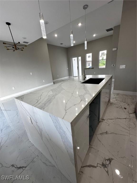 kitchen with a spacious island, hanging light fixtures, and light stone countertops