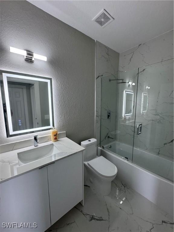 2610 34th St SW, Lehigh Acres, FL 33976 - full bathroom with a textured wall, toilet, enclosed tub / shower combo, vanity, and marble finish floors