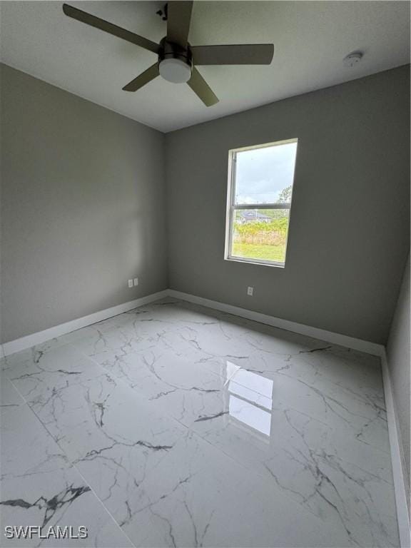 2610 34th St SW, Lehigh Acres, FL 33976 - spare room with baseboards, light marble finish flooring, and a ceiling fan