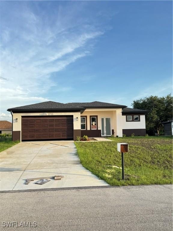 2610 34th St SW, Lehigh Acres, FL 33976 - prairie-style house featuring a garage, concrete driveway, stucco siding, french doors, and a front lawn