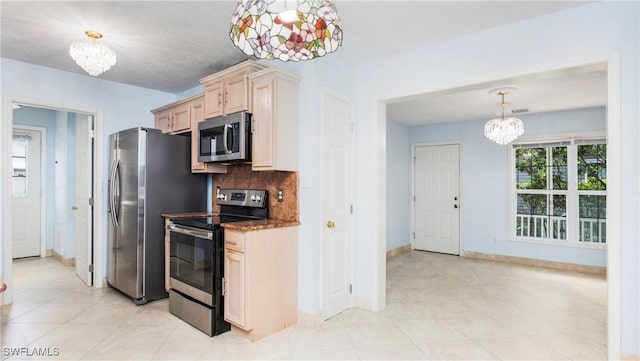 kitchen featuring hanging light fixtures, appliances with stainless steel finishes, a notable chandelier, and backsplash