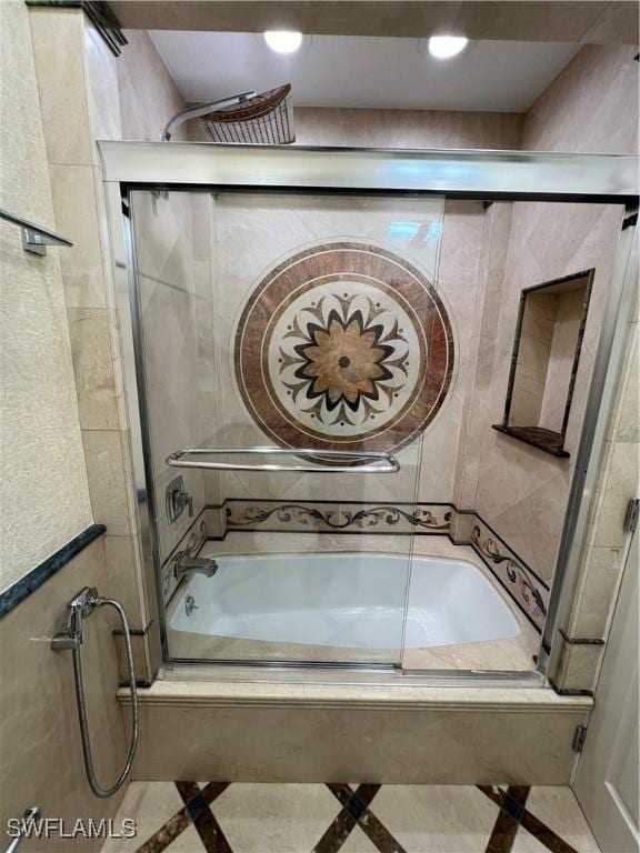 bathroom featuring bath / shower combo with glass door and tile walls