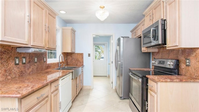 kitchen with light stone counters, sink, stainless steel appliances, and light brown cabinets