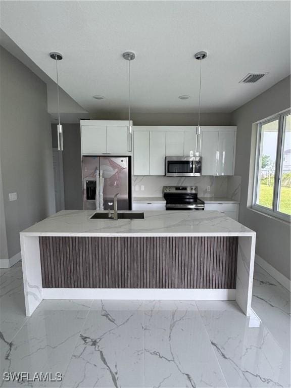 2810 27th St SW, Lehigh Acres, FL 33976 - kitchen featuring stainless steel appliances, a sink, baseboards, light marble finish floors, and white cabinetry