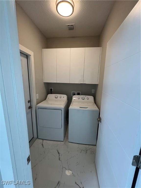 2810 27th St SW, Lehigh Acres, FL 33976 - washroom featuring cabinet space, washing machine and clothes dryer, light marble finish flooring, and a textured ceiling