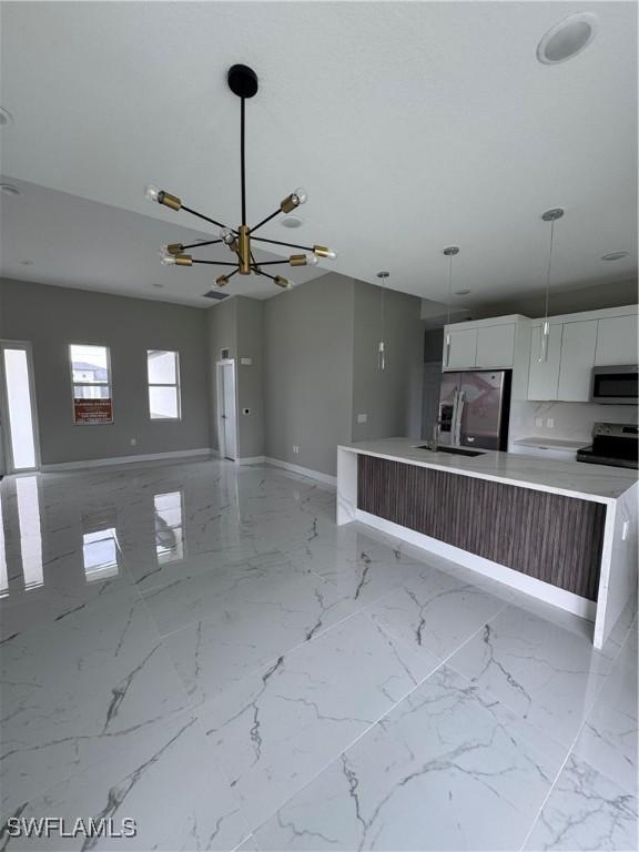 2810 27th St SW, Lehigh Acres, FL 33976 - kitchen with stainless steel appliances, baseboards, white cabinets, a chandelier, and light countertops
