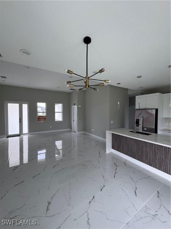 2713 26th St SW, Lehigh Acres, FL 33976 - unfurnished living room with a chandelier, baseboards, and a sink