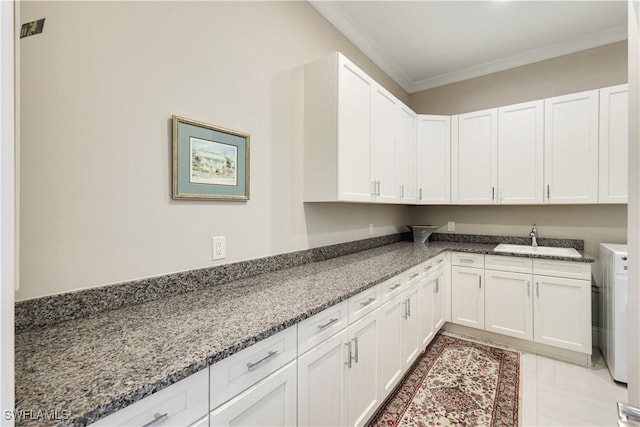 kitchen with crown molding, stone countertops, a sink, and white cabinets