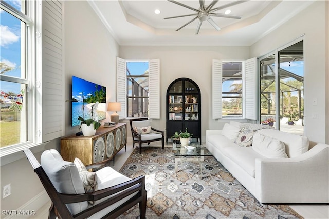 living area featuring baseboards, a raised ceiling, and recessed lighting