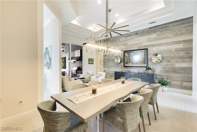 dining space with light tile patterned floors, a notable chandelier, an accent wall, baseboards, and a raised ceiling