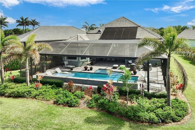 back of house with a tile roof, a yard, roof mounted solar panels, a lanai, and an outdoor pool