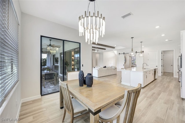 dining area featuring a healthy amount of sunlight, ceiling fan with notable chandelier, and light hardwood / wood-style flooring