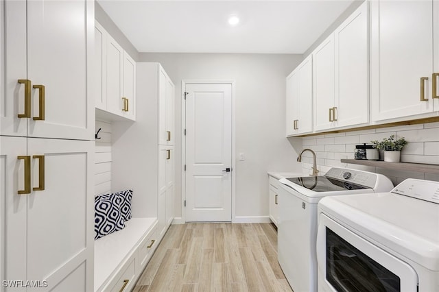 laundry area featuring cabinets, independent washer and dryer, light hardwood / wood-style floors, and sink