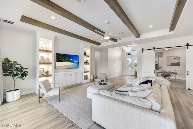 living room with beamed ceiling, ceiling fan, a barn door, and light hardwood / wood-style flooring