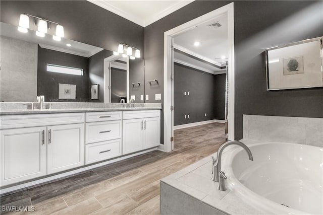 bathroom featuring vanity, hardwood / wood-style floors, crown molding, and a relaxing tiled tub