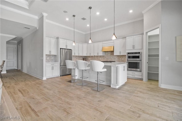 kitchen with hanging light fixtures, white cabinets, stainless steel appliances, and a center island