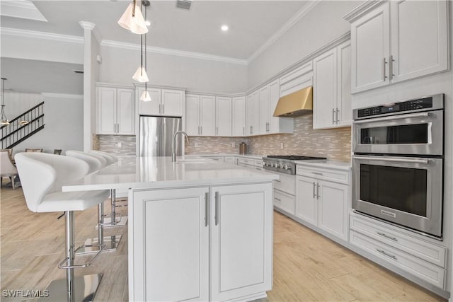 kitchen featuring white cabinetry, extractor fan, appliances with stainless steel finishes, and pendant lighting