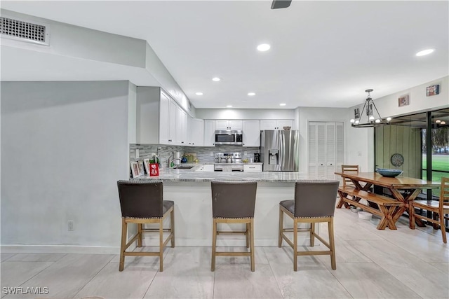 kitchen with visible vents, white cabinets, appliances with stainless steel finishes, hanging light fixtures, and a sink