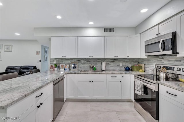 kitchen with appliances with stainless steel finishes, a sink, visible vents, and white cabinetry