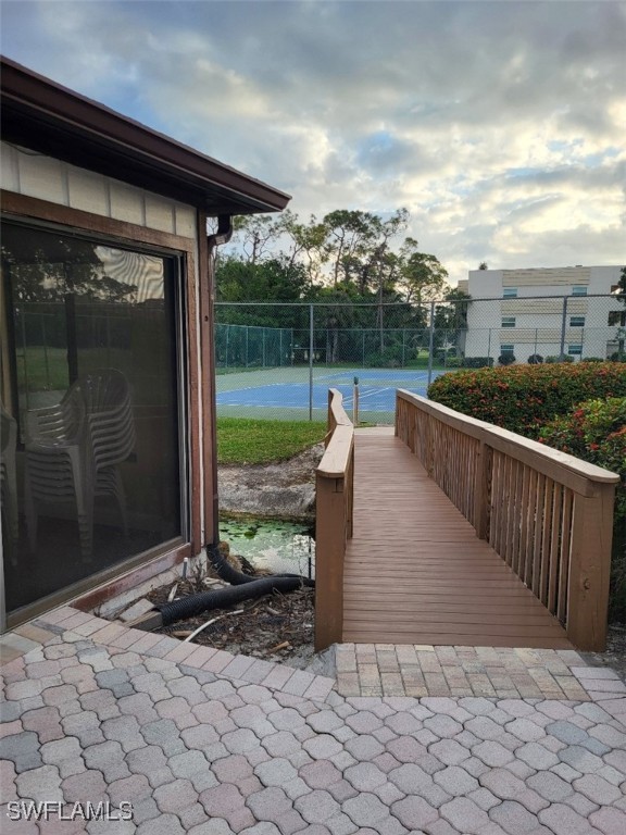 view of community with a tennis court and fence