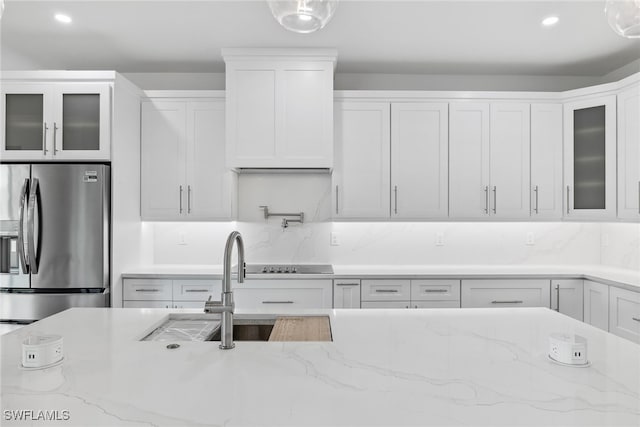 kitchen featuring glass insert cabinets, white cabinetry, stainless steel refrigerator with ice dispenser, and light stone countertops