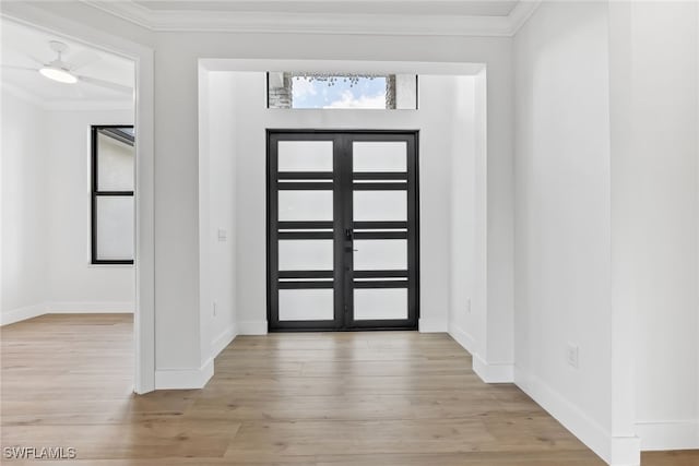 foyer with french doors, baseboards, crown molding, and light wood finished floors