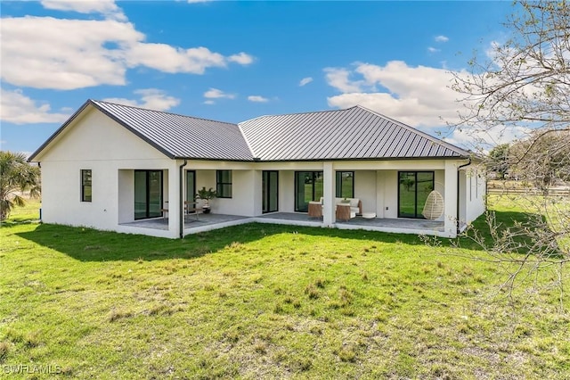 rear view of property featuring a yard, a standing seam roof, a patio, and metal roof