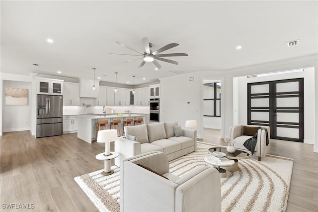 living area with ornamental molding, visible vents, and light wood-style floors