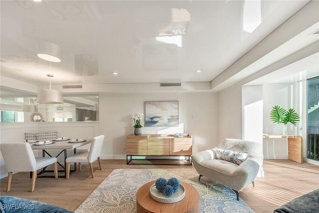 living room featuring wood finished floors, visible vents, and baseboards