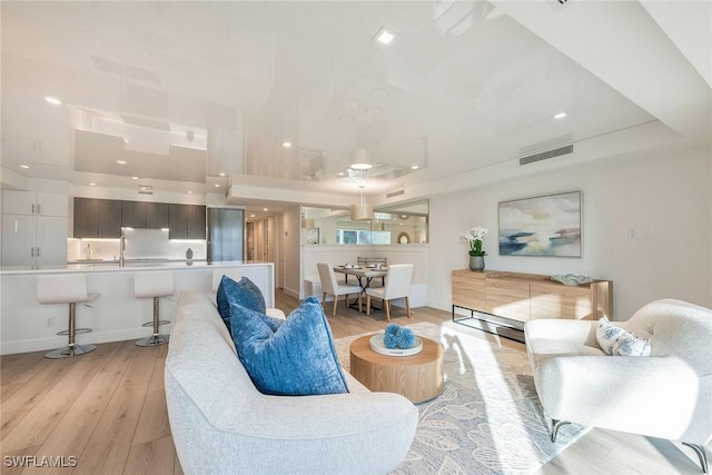 living area featuring recessed lighting, light wood-style floors, and visible vents