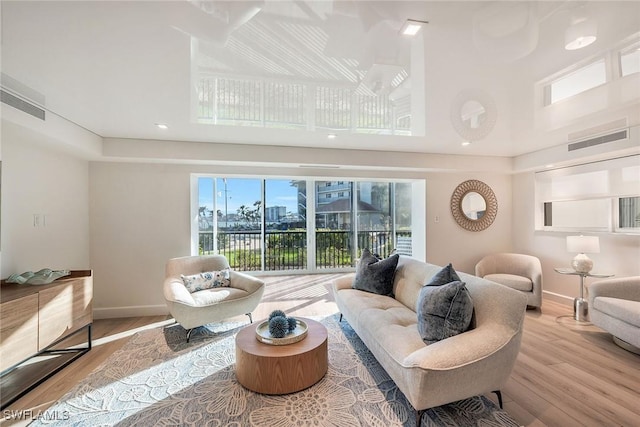 living room featuring visible vents, baseboards, and wood finished floors