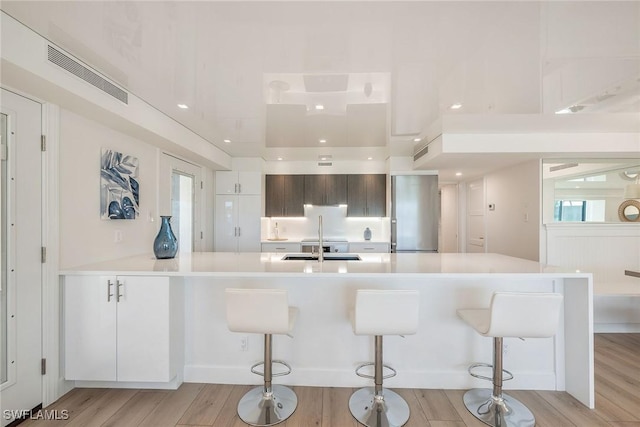 kitchen with light wood-style floors, visible vents, light countertops, and a breakfast bar area