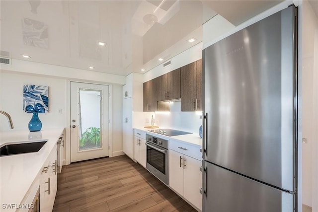 kitchen with recessed lighting, light countertops, appliances with stainless steel finishes, a sink, and wood finished floors