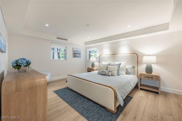 bedroom with recessed lighting, visible vents, baseboards, light wood-style floors, and a raised ceiling